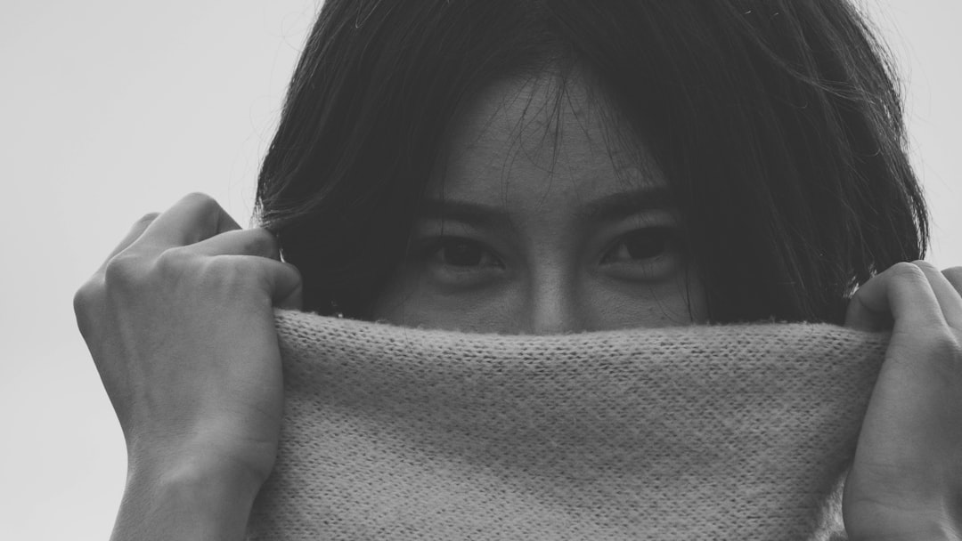 grayscale photo of woman covering her face with textile